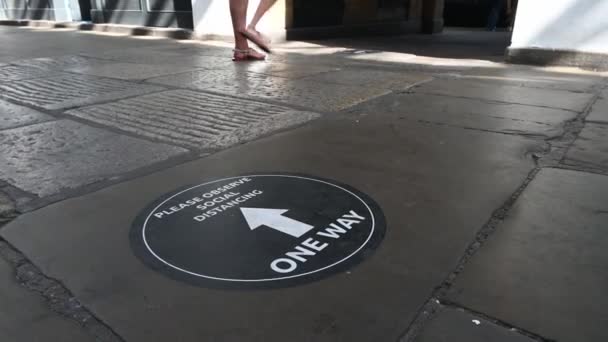 "Ein COVID-Schild auf dem Boden mit der Aufschrift "One Way" und der Aufforderung, soziale Distanzierung zu beachten — Stockvideo