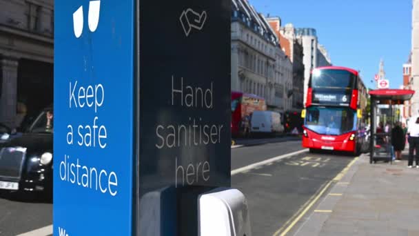 "Un primer plano de un cartel de COVID pidiendo a la gente a distancia social y desinfectar la mano al lado de una carretera en Londres — Vídeos de Stock