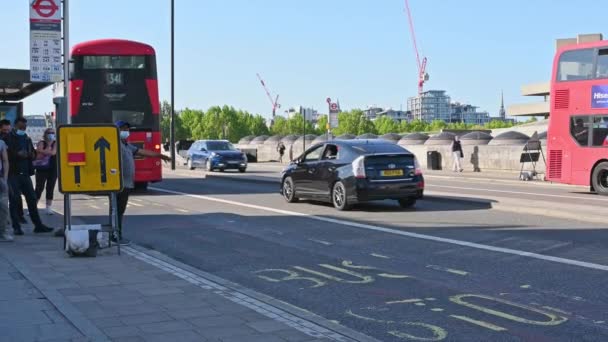 "Een man met een gezichtsmasker zwaait over een Red London Double Decker Bus — Stockvideo