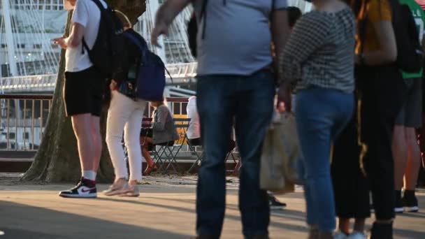 "Pessoas sentadas junto ao rio Tâmisa, na margem sul, desfrutando de uma bebida em uma noite de verão — Vídeo de Stock