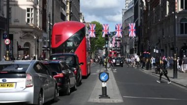 LONDON - 16 Mayıs 2022: Oxford Caddesi, Union Jack bayrağıyla süslenmiş, çift katlı otobüsler ve taksiler geçiyordu.
