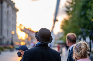 Londra, İngiltere - 14 Eylül 2022: Siyah ceketli ve melon şapkalı bir adamın arkadan Londra Gözü 'ne ve arka planda gün batımına doğru bakan görüntüsü