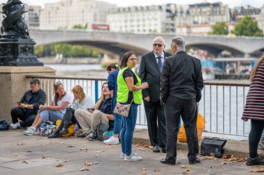 Londra, İngiltere - 14 Eylül 2022: Yüksek görünürlüklü ceket giyen bir kadın Londra 'da Güney Şeria boyunca kuyrukta bekleyen insanlarla konuşuyor