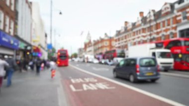 Brixton, Londra, İngiltere 'deki şehir caddesinde yayaların ve trafiğin odak noktası dışında. Sokaktan geçen alışveriş merkezleri, yoldan geçen ikonik kırmızı otobüsler. 4k
