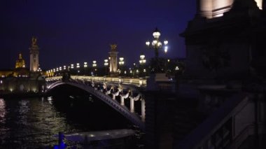 Paris 'teki Seine Nehri' nin karşısındaki Alexandre III köprüsünün romantik gece sahnesi. Paris 'te gece vakti ünlü Fransız köprüsünde ışık direkleri ve heykeller