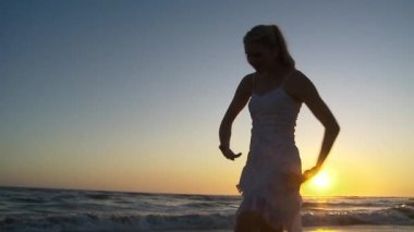 Gün batımında genç bir kadın plaj balesi