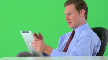 İş adamı yeşil ekranda tableti üzerinde çalışıyor.
