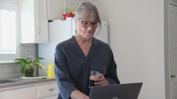 Mujer Mayor Caucásica Usando Computadora Portátil Cocina Mientras Bebe Café — Vídeos de Stock