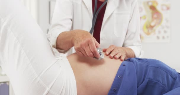 Médico Senior Revisando Vientre Mujer Embarazada — Vídeos de Stock