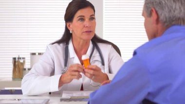 Yaşlı hastaya ilaç yazan kadın doktor.