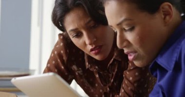Tablet bilgisayarda çalışan iki siyah ve Hispanik iş kadın kapatmak