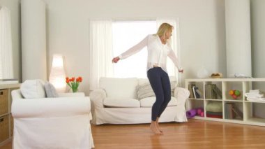 Olgun bir kadın kanepede zıplıyor ve oturma odasında dans ediyor.