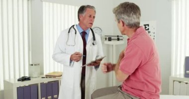 Yaşlı bir hasta kolundaki ağrı hakkında doktorla konuşuyor.