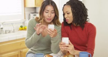 İki kadın en iyi akıllı telefonlar kullanarak ve kahvaltı arkadaşlar