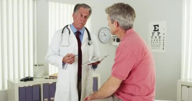 Doktor ofiste yaşlı bir hastayla konuşuyor.