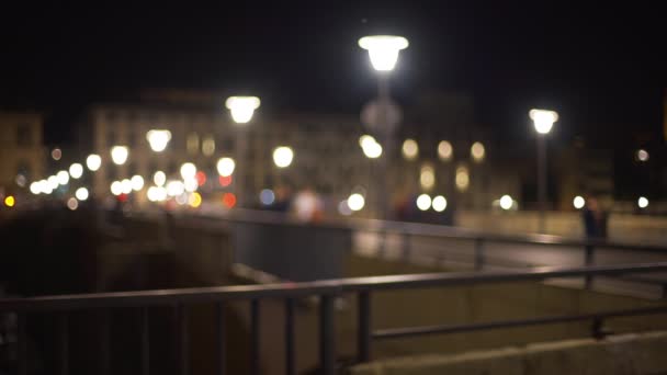 街路灯と人々が歩いてヨーロッパの夜のシーンのぼやけた背景プレート フィレンツェの橋の上のボケライトアーノ川を渡ってイタリア — ストック動画
