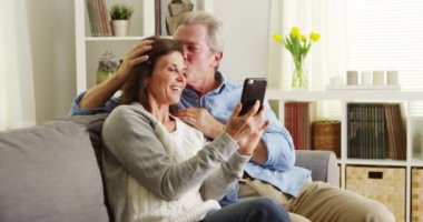 Kanepede akıllı telefon kullanan yaşlı çift.