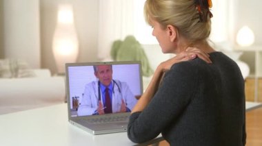 Orta yaşlı bir kadın doktorla görüntülü konuşma yapıyor.