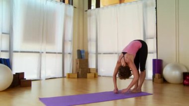 Genç bir kadın paspasın üzerinde pilate hareketi yapıyor.