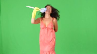 Tuvalet fırçası ve süngeriyle şarkı söyleyen bir yıldız gibi davranan genç bir kadın.