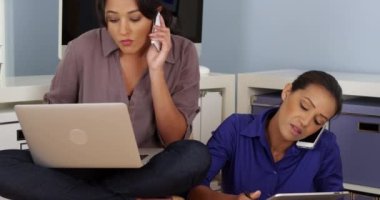 Cep telefonlarında konuşurken birlikte çalışan siyah ve Hispanik iş kadınları