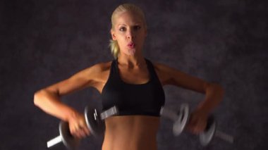 Güçlü sarışın kadın ağırlık kaldırıyor.