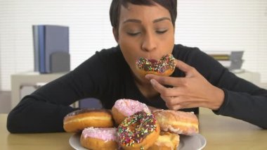 Afro-Amerikalı iş kadını bir yığın çörek yiyor.