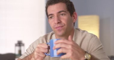 Evde bir fincan kahveyle rahatlayan bir adam.