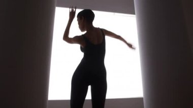 Parlak ışığın önünde dans eden Afrikalı Amerikalı kadın