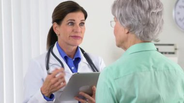 Kadın doktor tabletli hastayla konuşuyor.