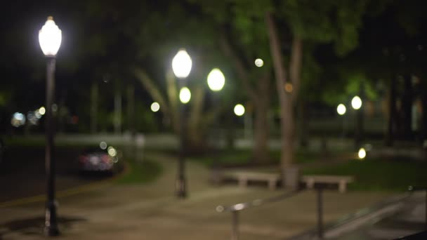 夜间黑暗城市公园的视频背景板失焦 从建筑台阶上看到有人行道和树木的城市公园 — 图库视频影像