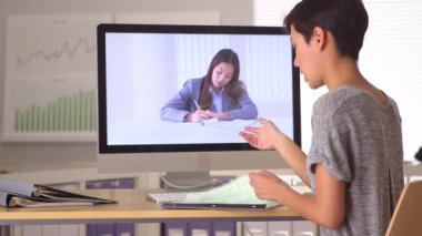 Çinli iş kadını iş arkadaşıyla Skype 'ta notları tartışıyor.