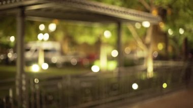 Akşamları güzel bir şehir parkının arka planında. Şehir parkında ağaçlarla dolu boş bir patikanın Bokeh çekimi. 4k