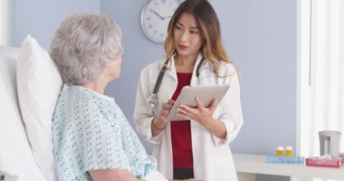 Japon doktor hastane yatağında yaşlı hasta ile konuşma