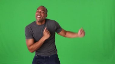 Kotlu ve tişörtlü genç adam dans ediyor.