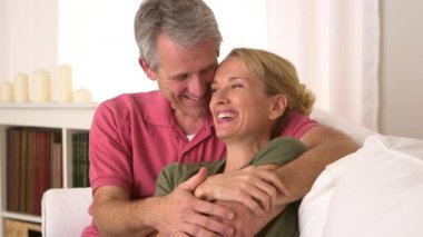 Yaşlı çift kanepede konuşuyor ve sarılıyorlar.