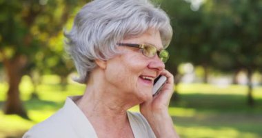 Büyükannem parkta akıllı telefonuyla konuşuyor.