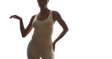 Beyaz cüppeli siyah kadın beyaz arka planda zarif bir dans sergiliyor.