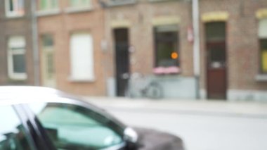 Şehir caddesinde ön planda arabaları olan tuğlalı binaların önünden geçen trafiğin odak alanı dışında. Yeşil ekran bileşimi için bulanık görüntü arkaplanı. 4k