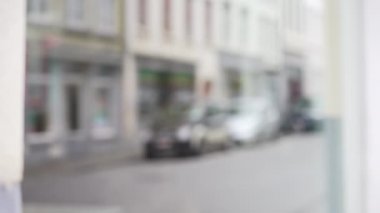 Şehir sokağının arka planında, yakın çekim için geçen arabalar var. Avrupa kentini bileşim için yansıtan mağaza vitrininin bulanık video arkaplanı. 4k