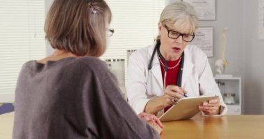 Kadın kıdemli Doktor tablet konuşan hasta