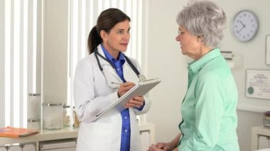 Başhekim hastayla konuşurken not alıyor.