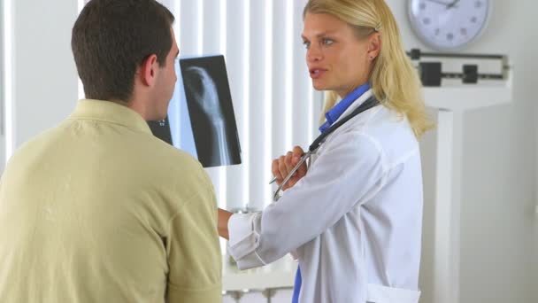 Vrouwelijke Dokter Die Röntgenfoto Bekijkt Met Mannelijke Patiënt — Stockvideo
