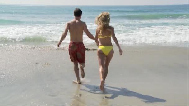 ビーチで海の波に遭遇した若いカップル — ストック動画