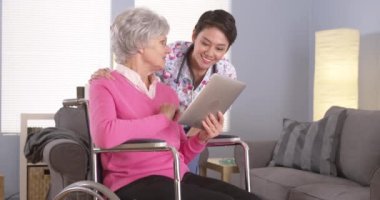 Çinli kadın ve yaşlı hasta tablet ile konuşmak