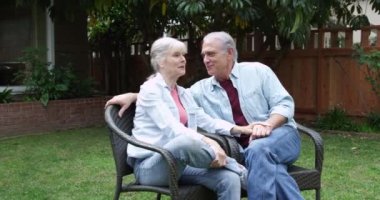 Yaşlı çift bahçede oturmuş konuşuyor.