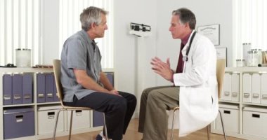 Kıdemli doktor olgun bir hastaya danışıyor.