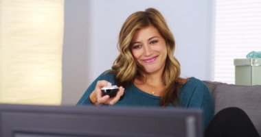 Genç kadın elinde uzaktan kumandalı televizyon izlerken