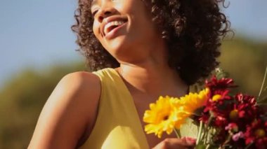 gülen ve çiçek tutan genç bir kadın