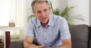 Olgun adam koltukta oturmuş konuşuyor.